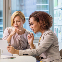Two women discussing a project in front of them.